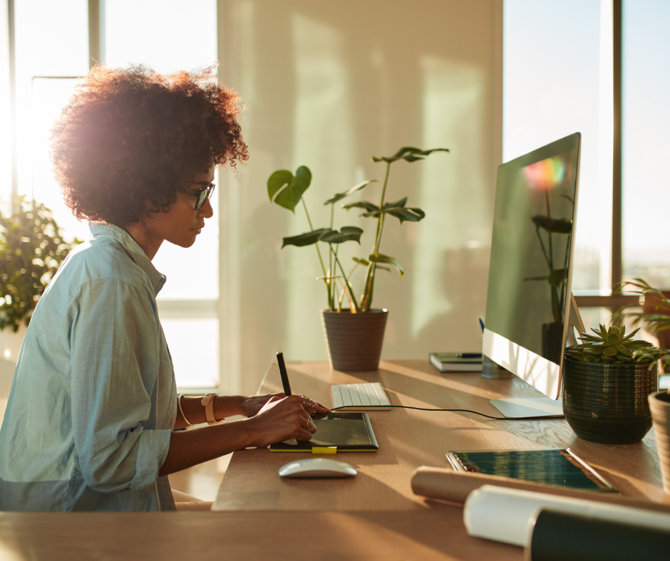 Side view of female graphic designer working with digital tablet and pen on a computer in office. 