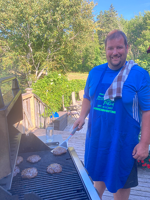 Photo of Dave outside on the deck BBQing burgers on the grill.